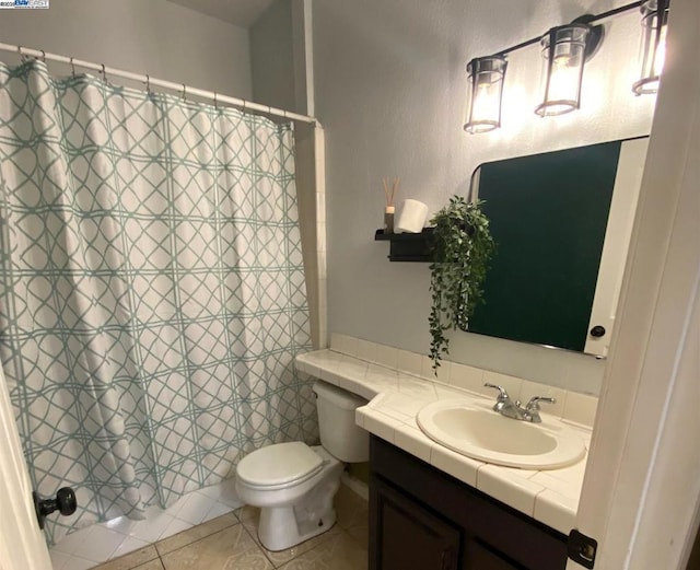 bathroom featuring tile patterned flooring, vanity, toilet, and walk in shower