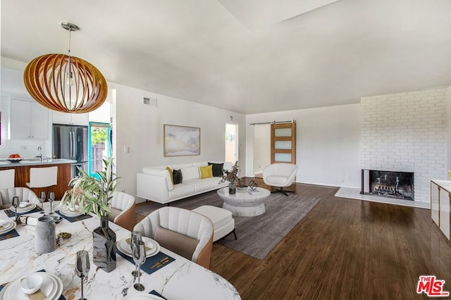 living room with plenty of natural light, a barn door, dark hardwood / wood-style floors, and a fireplace