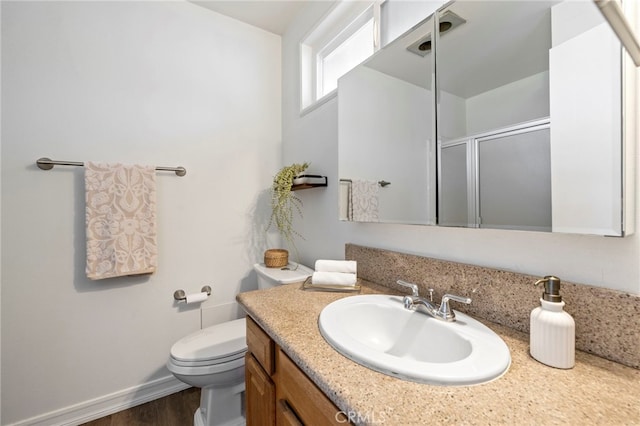 bathroom featuring toilet, hardwood / wood-style floors, a shower with shower door, and vanity