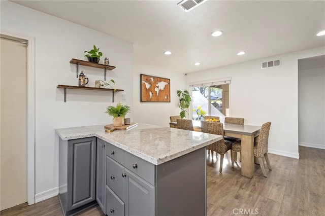 kitchen with light stone countertops, gray cabinets, and wood-type flooring