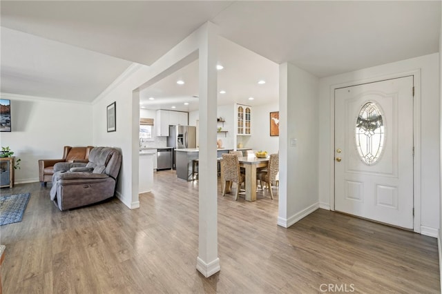 entrance foyer with crown molding, light hardwood / wood-style flooring, and sink