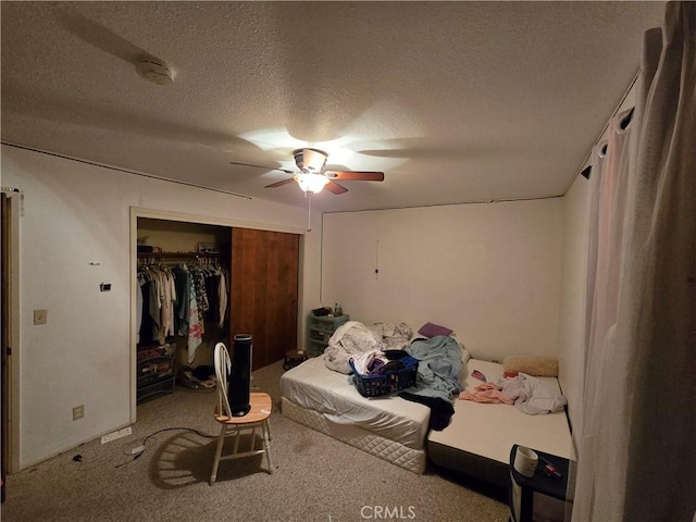 bedroom with ceiling fan, carpet flooring, a closet, and a textured ceiling
