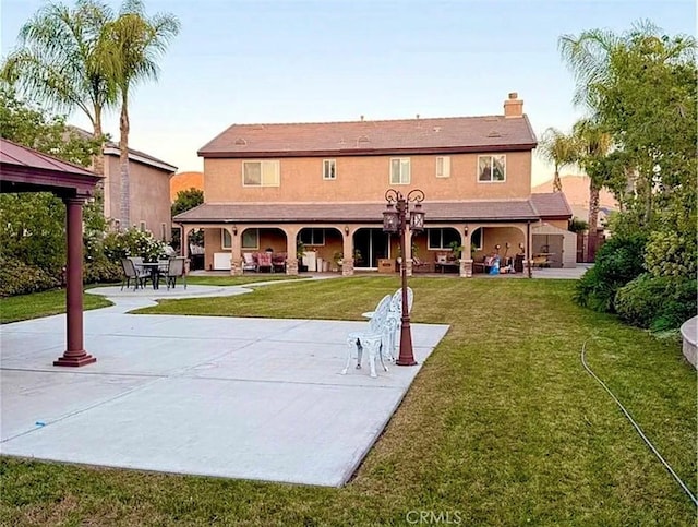 rear view of property featuring a yard and a patio