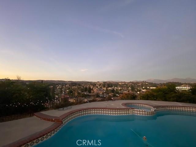 view of pool featuring a pool with connected hot tub and fence