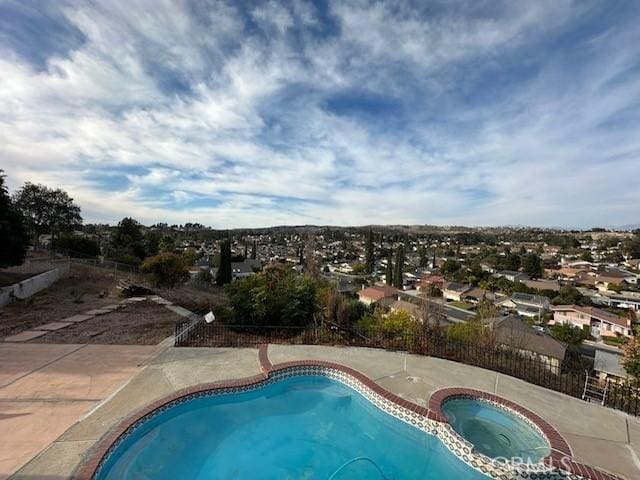 view of swimming pool featuring a pool with connected hot tub and fence