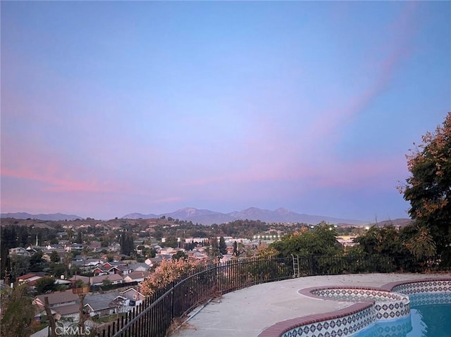 exterior space with a mountain view, a pool with connected hot tub, and fence