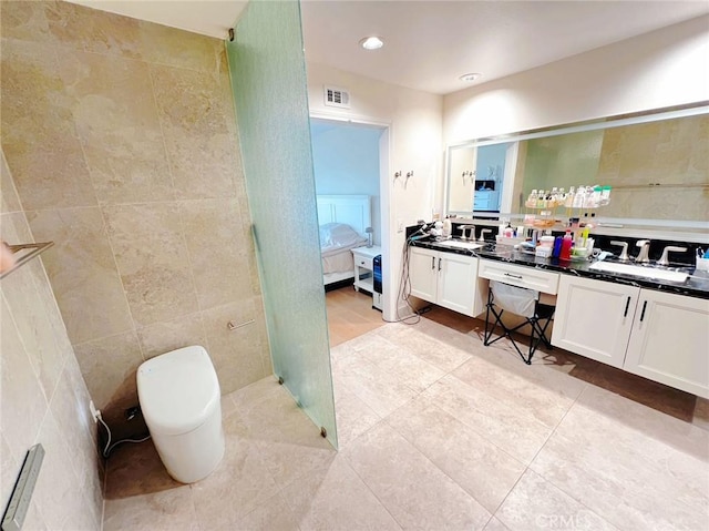 bathroom with vanity, a shower, tile patterned floors, and tile walls