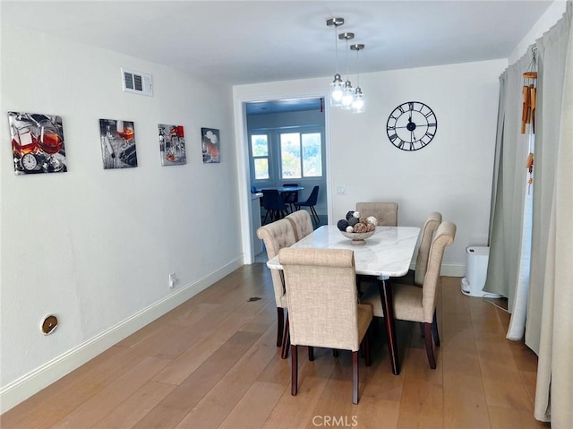 dining room featuring visible vents, light wood-type flooring, and baseboards
