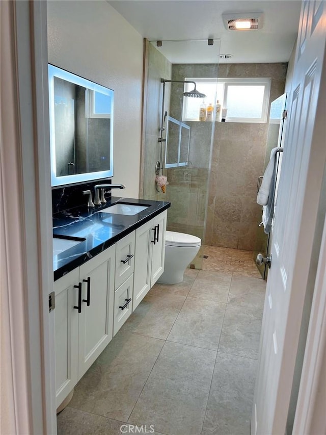 bathroom featuring walk in shower, double vanity, a sink, and toilet