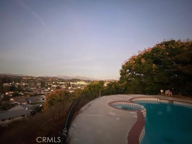 pool at dusk with an in ground hot tub