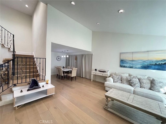 living room featuring light wood-style floors, high vaulted ceiling, recessed lighting, and stairs