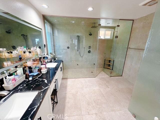 bathroom with a walk in shower, double vanity, a sink, and recessed lighting