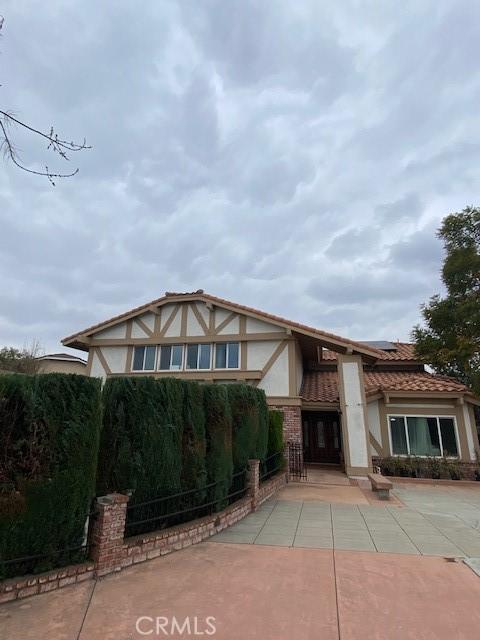 english style home with a tile roof, stucco siding, and roof mounted solar panels
