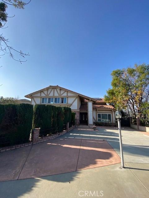 tudor house with a tile roof, fence, and stucco siding
