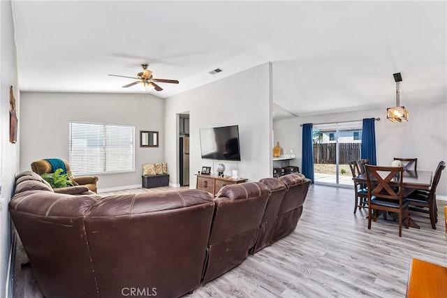 living room featuring ceiling fan, lofted ceiling, and light hardwood / wood-style flooring