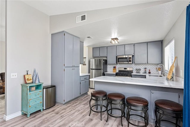 kitchen featuring decorative backsplash, kitchen peninsula, sink, and appliances with stainless steel finishes