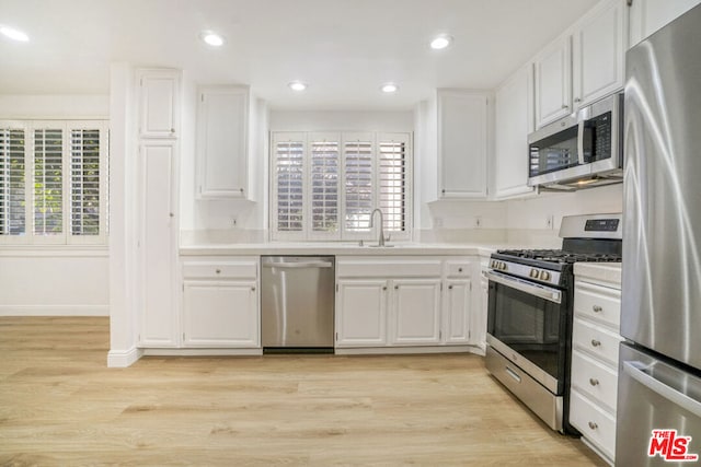 kitchen with sink, appliances with stainless steel finishes, plenty of natural light, light hardwood / wood-style floors, and white cabinetry