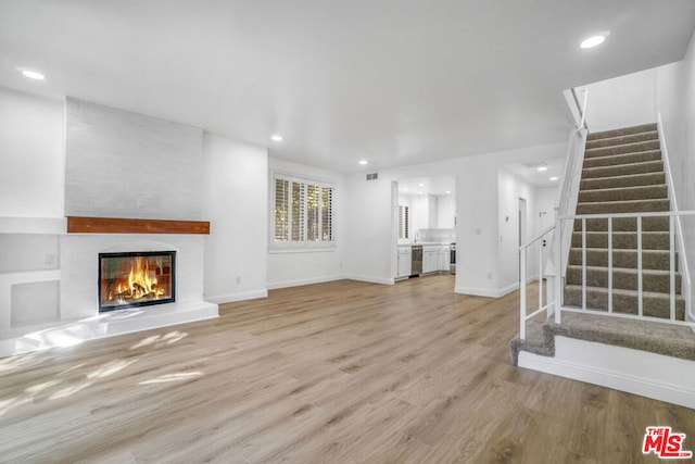 unfurnished living room featuring a large fireplace and light hardwood / wood-style floors