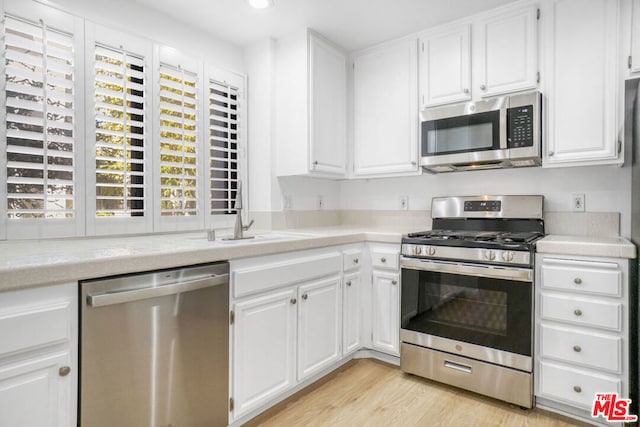 kitchen with white cabinetry, sink, stainless steel appliances, and light hardwood / wood-style floors