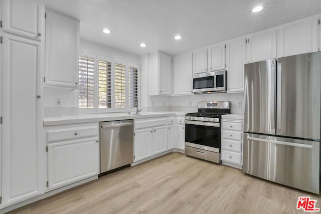 kitchen featuring appliances with stainless steel finishes, light hardwood / wood-style flooring, white cabinetry, and sink