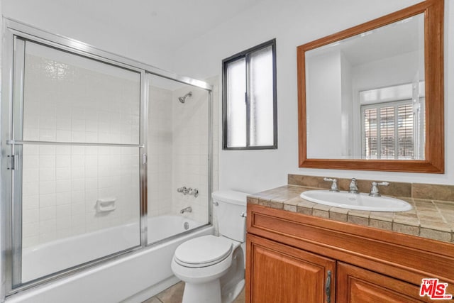 full bathroom featuring tile patterned floors, vanity, bath / shower combo with glass door, and toilet