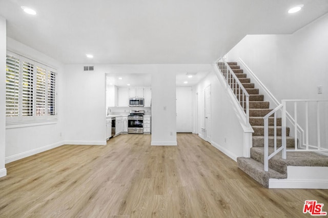 unfurnished living room with light wood-type flooring and sink