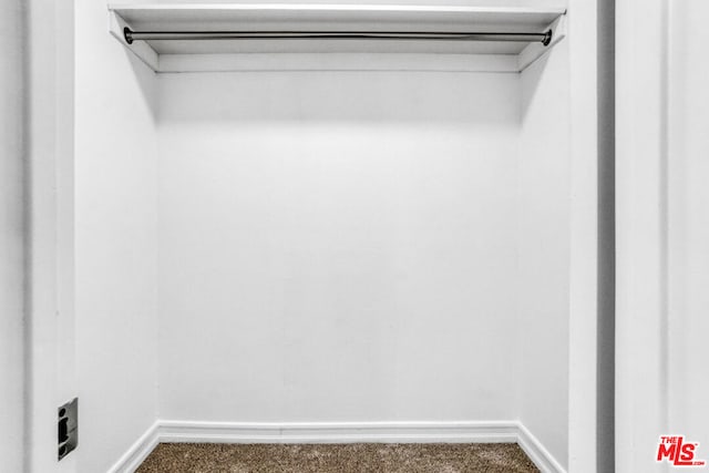 walk in closet with dark colored carpet