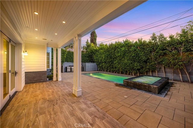 patio terrace at dusk with a pool with hot tub