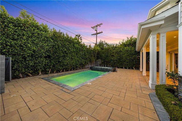 pool at dusk with a patio area