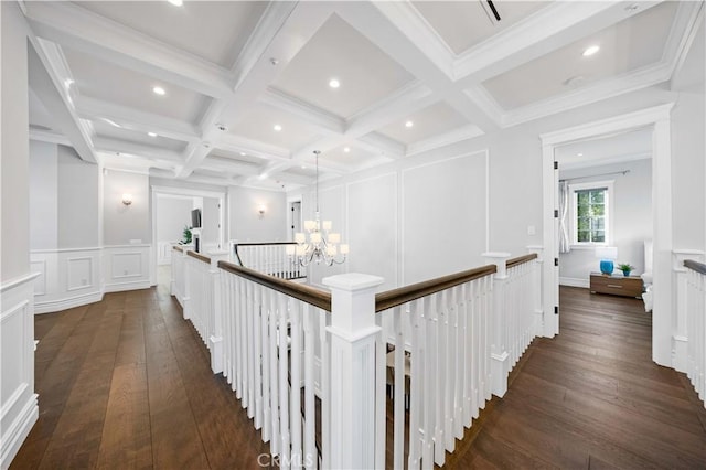 hall with coffered ceiling, dark hardwood / wood-style flooring, beamed ceiling, a notable chandelier, and ornamental molding