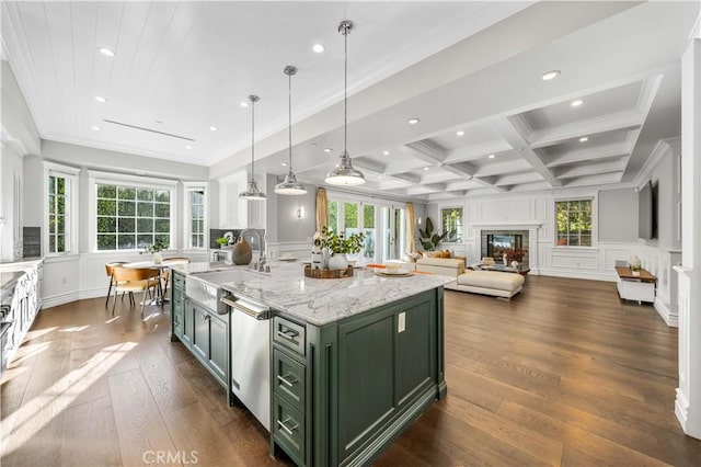 kitchen featuring coffered ceiling, sink, green cabinetry, an island with sink, and beamed ceiling