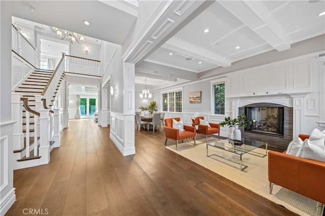 living room with beam ceiling, plenty of natural light, wood-type flooring, and a notable chandelier