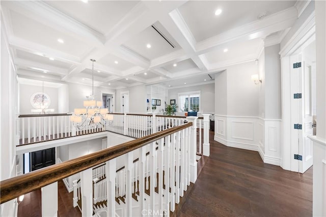 hall featuring coffered ceiling, beam ceiling, dark wood-type flooring, and an inviting chandelier