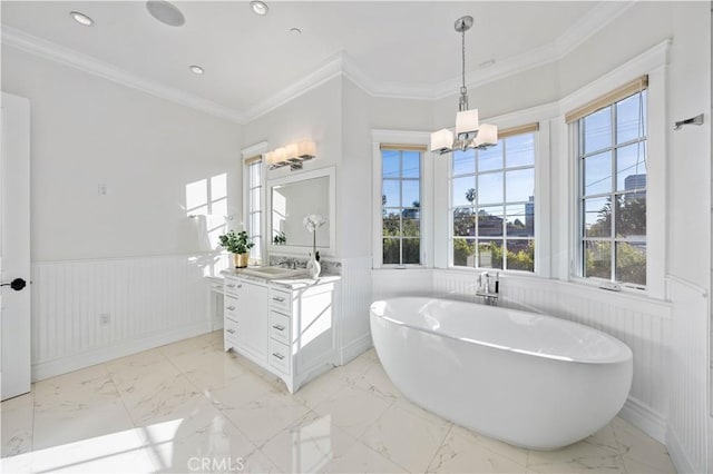 bathroom with a chandelier, vanity, a bathtub, and ornamental molding