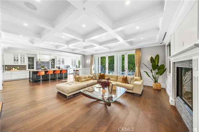 living room featuring beam ceiling, a brick fireplace, coffered ceiling, and hardwood / wood-style floors