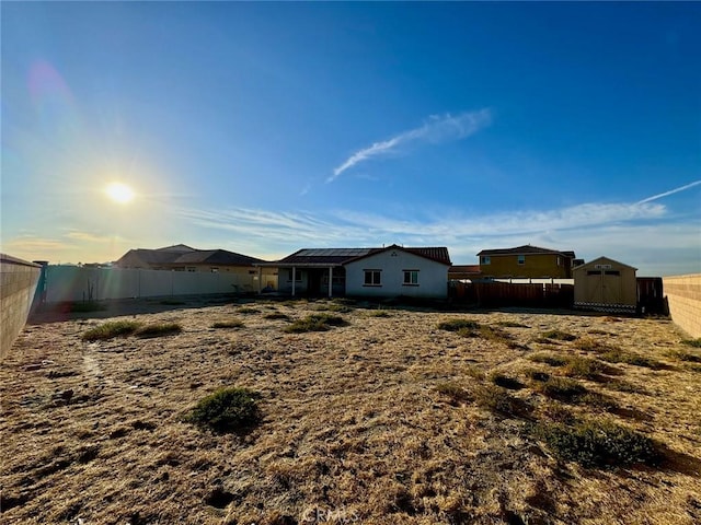 rear view of property with solar panels and a storage shed