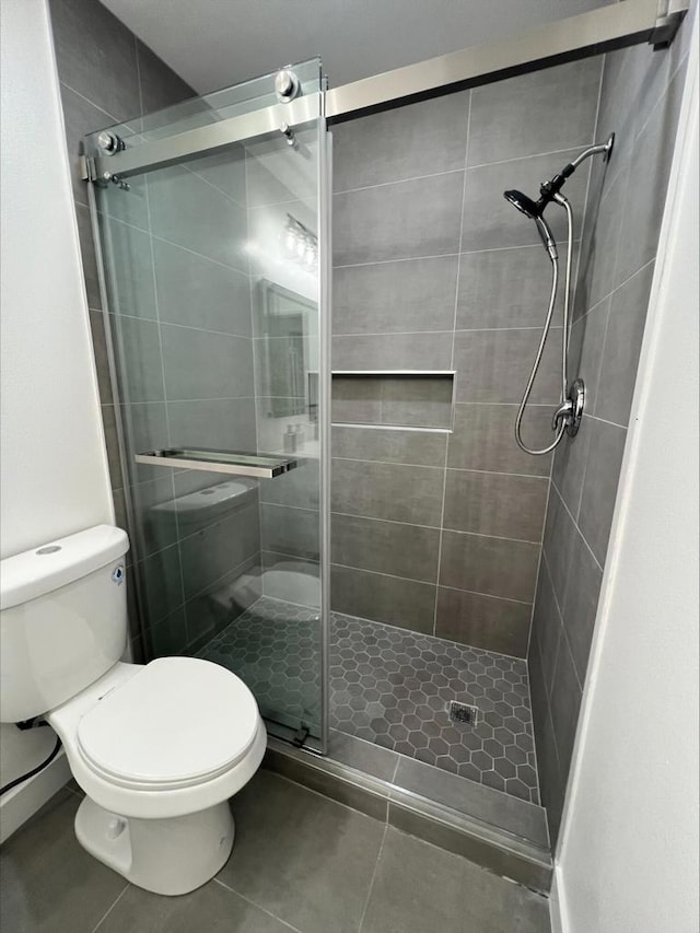 bathroom with a shower with shower door and toilet