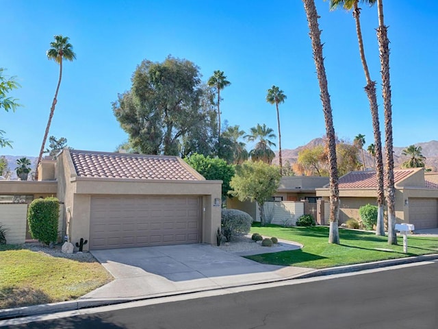 view of front of home featuring a mountain view, a front lawn, and a garage