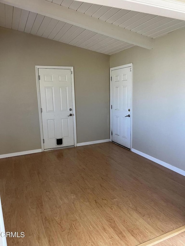 empty room with beam ceiling and wood-type flooring