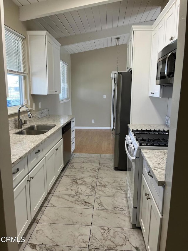 kitchen featuring white cabinets, sink, light stone countertops, appliances with stainless steel finishes, and beam ceiling