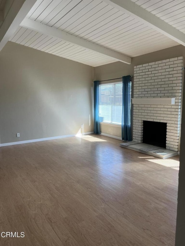 unfurnished living room featuring a fireplace, beamed ceiling, and wood-type flooring