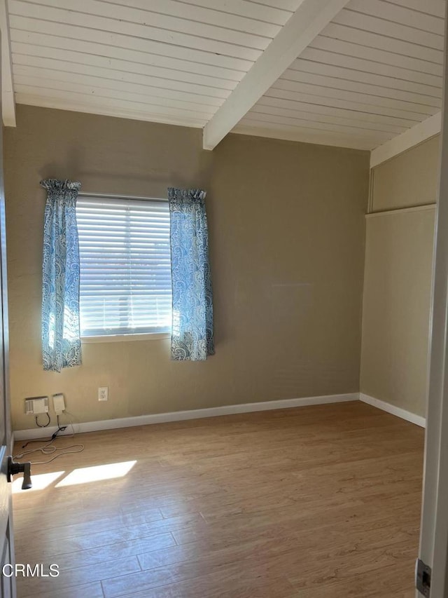 empty room featuring vaulted ceiling with beams, wooden ceiling, and wood-type flooring