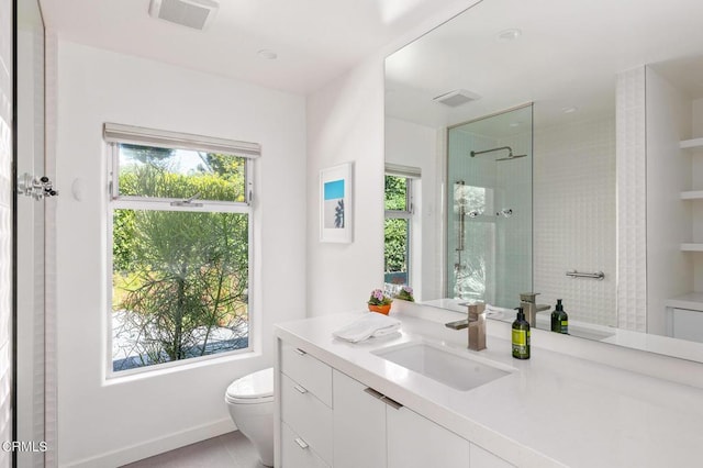 bathroom featuring a tile shower, vanity, toilet, and plenty of natural light