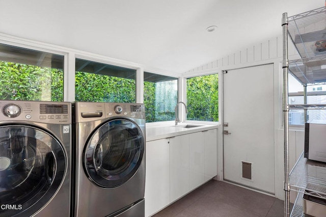 laundry room with dark tile patterned flooring, cabinets, sink, and washing machine and clothes dryer