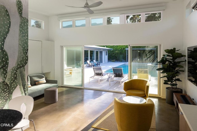 doorway to outside with concrete flooring, a high ceiling, and ceiling fan