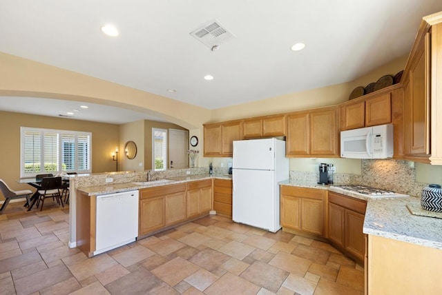 kitchen with kitchen peninsula, white appliances, light stone counters, and sink