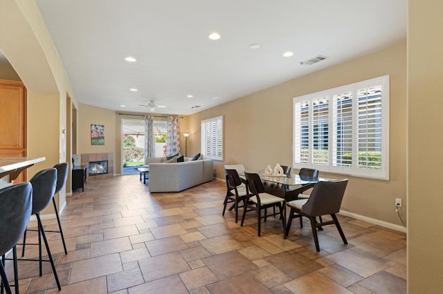 dining space featuring ceiling fan, a healthy amount of sunlight, and a fireplace