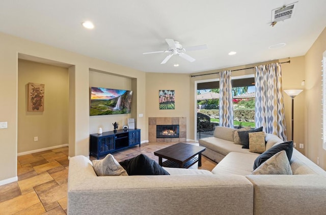 living room with ceiling fan and a tiled fireplace