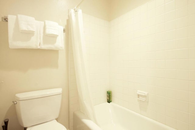 bathroom with shower / tub combo with curtain and toilet