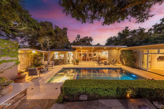 pool at dusk with a patio area